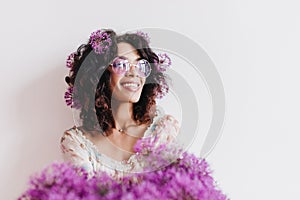 Refined african girl in good mood posing with alliums. Indoor photo of trendy young woman in sungla