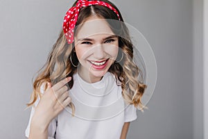 Refined caucasian girl laughing to camera during indoor photoshoot. Amazing good-humoured lady with