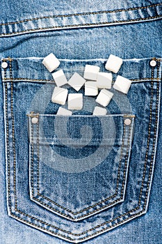 Refined sugar on denim background. Pocket of jeans full of refined sugar. Diet concept. Pocket full of sugar as symbol