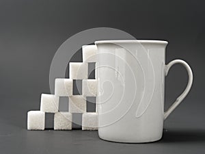 Refined sugar lump white and white cup on a gray background