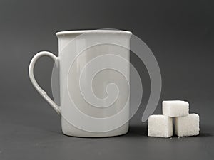 Refined sugar lump white and white cup on a gray background