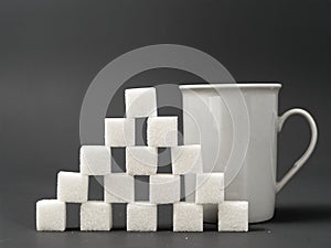 Refined sugar lump white and white cup on a gray background