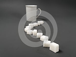 Refined sugar lump white and white cup on a gray background