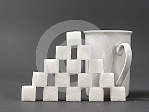 Refined sugar lump white and white cup on a gray background