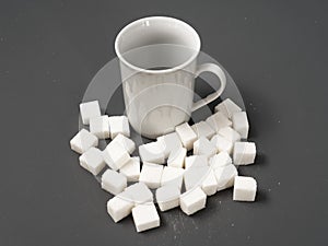 Refined sugar lump white and white cup on a gray background