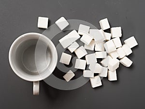 Refined sugar lump white and white cup on a gray background