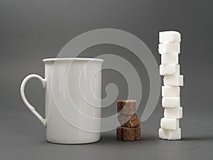 Refined sugar lump white and white cup on a gray background