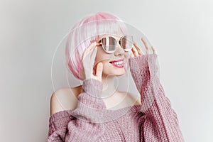 Refined young white girl in sparkle glasses and purple woolen sweater posing on light background. Studio portrait of