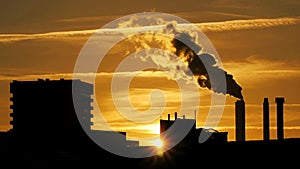 Refinery plant silhouette with chimney smoke against sunset