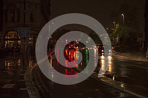 The reflecion of traffic and lights in the wet streets of london during night with vehicles on the road