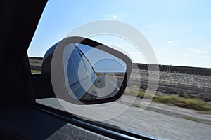 Reflected road in rearview mirror. View from car side mirror driving on asphalt road
