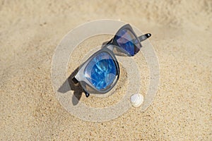 Reflecting sunglasses on sandy beach