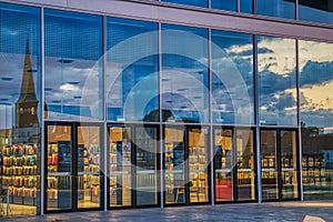 Reflection of Aarhus skyline on the glazed entrance of the Dokk1 library at sunset features an intense twilight sky with clouds