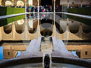 reflection of Al Nasrid building in pond water with tourist