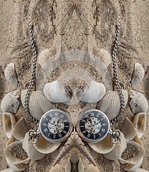 Reflection of Antique pocket watch and shells in sand on the beach