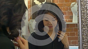 Reflection of an asian woman on a mirror as she tries earrings in a jewellery store