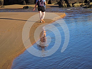 Reflection of a backpacker and footprints on sand