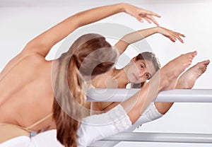 Reflection, ballerina and stretching legs on barre in classroom, practice and student exercise. Ballet, flexibility and
