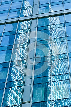 Reflection in blue glass wall of modern office building