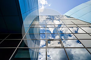 Reflection of blue sky with clouds in an office building window