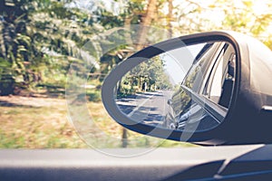 Reflection blurred roadway view on side mirror car during driving car on the way.