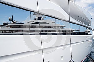 Reflection of a boat on a glossy surface of a huge yacht at sunny day, the chrome plated handrail, megayacht is moored photo