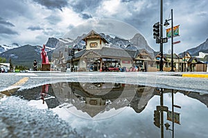 Reflection of a building with mountains in a puddle in the Village Square in Canmore, Alberta
