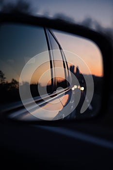 reflection in car rear mirror sunset on the road