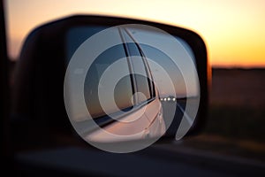 reflection in car rear mirror sunset on the road