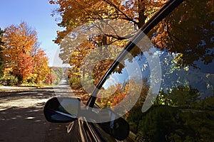 The reflection from the car window of the landscape of mountain road with autumn leaf color