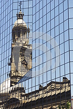 Reflection of the Cathedral of Santiago tower in the windows of the modern building at Plaza de Armas in Santiago, Chile. photo