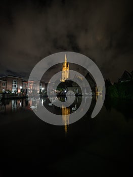 Reflection of catholic gothic cathedral church of our lady Onze Lieve Vrouwekerk in river canal channel Bruges Belgium