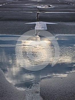 Reflection of a clouds in a puddle at road at autumn cloudy day in Belgrade