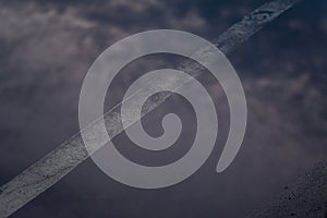 Reflection of the clouds and sky on the flood puddle on the road