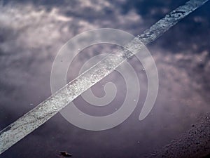 Reflection of the clouds and sky on the flood puddle on the road