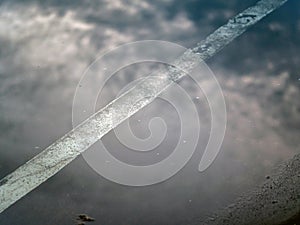 Reflection of the clouds and sky on the flood puddle on the road