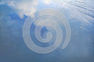 Reflection of clouds in waves at the beach