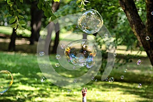 Reflection of the colorful sunset sky in a big soap bubble with kids hand. Happy life concept.