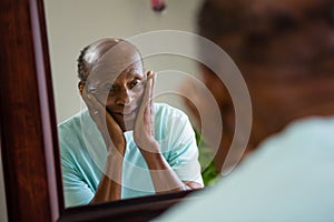 Reflection of concerned senior man on mirror