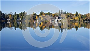 Reflection of the cottages and fall leaf colour in the lake district, Ontario, Canada