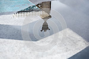 Reflection of Decorative historic metal fence in puddle after rain. Mysterious abstract, gate entrance in dreams