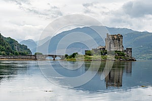 Reflection of Eilean Donan Castle, Scotland and the bridge in waters of Loch Duich in typical Scottish cloudy weather