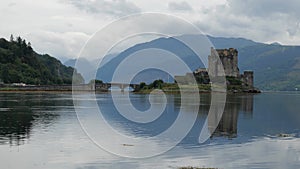 Reflection of Eilean Donan Castle, Scotland, UK and the bridge in waters of Loch Duich in Scottish cloudy weather