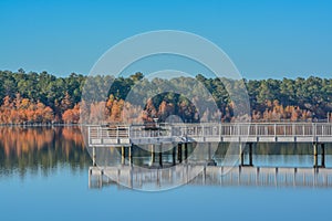 A reflection of the fishing pier and Fall leaf colors on Little Ocmulgee River in McRae, Georgia