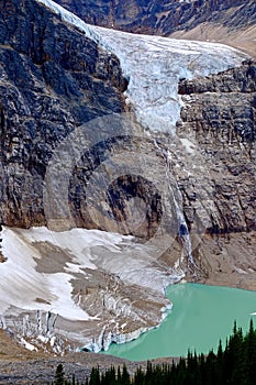 Reflection of glacier and waterfalls in alpine lake.