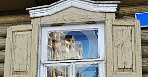 Reflection in the glass of the window of the old house of the new building