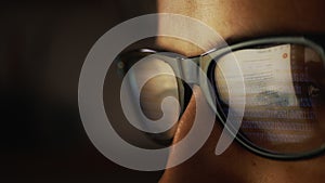 In the reflection of glasses on a male face, surfing the Internet and rows of binary code numbers. Cg