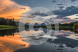 Reflection of Grand Tetons in Jackson Lake at sunset with beautiful clouds