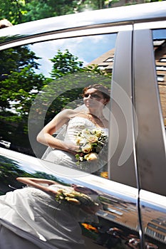 Reflection of happy bride in wedding limo window