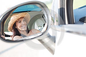 Reflection of happy woman in rearview mirror of car